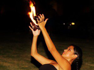 A woman holding onto fire in the dark