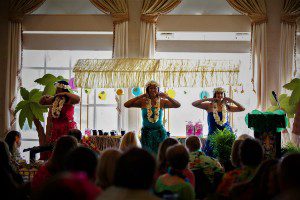 Three hula dancers perform in front of a crowd.