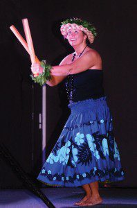 A woman in blue skirt and black top performing on stage.