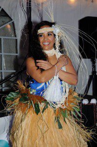 A woman in costume holding onto a hula girl.