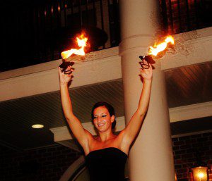 A woman holding fire torches up in the air.