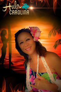 A woman in a hawaiian outfit smiling for the camera.