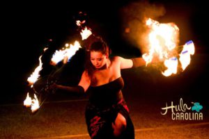 A woman in black dress and fire dancing.